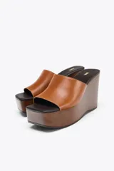 Sandalias de cuña color marrón con plataforma de madera y tira ancha de cuero sintético color caramelo.