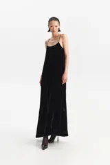 Vestido largo negro de tirantes finos, con escote recto en el frente y escote en V en la espalda. Presenta un calce holgado y bolsillos laterales.
