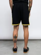 Bermuda deportiva negra con cintura elastizada y cordón ajustable. Presenta un escudo amarillo con estrellas en la pierna izquierda y detalles en amarillo y gris en los laterales y ruedo.