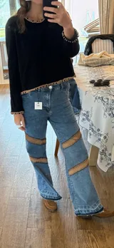 Pantalón de jean azul con corte holgado y apliques de gamuza marrón bordados a mano en los laterales.