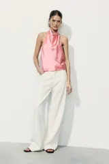 Top blanco satinado con cuello halter y escote fluido. Cierre en la espalda con botones.