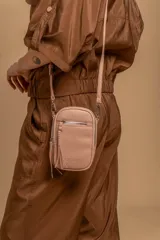 Bandolera compacta de símil cuero color rojo, con correa regulable y desmontable. Posee apertura superior, bolsillo frontal con cierre y bolsillo trasero abierto.