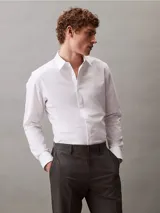 Camisa blanca de algodón, poliéster y elastano, de corte slim, manga larga y cuello en punta.