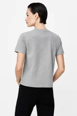 Remera blanca de algodón con estampado de flores azules y naranjas, de corte clásico y cuello redondo.