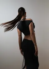 Conjunto de top corto negro de un solo hombro y falda larga negra con cordones laterales.