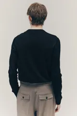 Buzo negro de punto fino suave con cuello redondo y corte slim fit. Presenta ribete acanalado en cuello, puños y bajo.