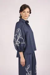 Camisa azul marino con bordados de flores blancas en mangas y ruedo.