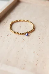 Pulsera elástica dorada con bolitas de acero quirúrgico hipoalergénico y dije de ojo turco.