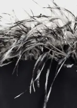 Vestido corto negro de fiesta con escote palabra de honor y adorno de plumas en el borde superior.