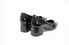 Zapato de salón negro con textura grabada, tacón cuadrado de 5 cm y puntera ligeramente cuadrada y redondeada.
