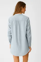 Vestido corto celeste de algodón con cuello mao, escote en V, mangas largas y dos bolsillos frontales.