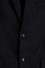 Blazer negro de corte slim fit, con solapas de muesca finas, ojal decorativo, botonadura sencilla, bolsillo superior insertado, bolsillos delanteros con solapa, dos bolsillos interiores, botones decorativos en los puños y abertura doble atrás. Forrado.