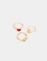 Set de tres anillos dorados de metal con diferentes dijes: un oso, un corazón rojo y la palabra 'Love'.