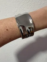 Brazalete ancho plateado con diseño irregular.