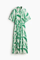 Vestido midi con cuello camisero, botonadura frontal, mangas cortas y cinturón para atar. Estampado de hojas verdes sobre fondo blanco.