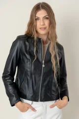 Campera de cuero ovino negro, estilo clásica, con cuello a la base, cierre frontal metálico y bolsillos laterales con cierre.