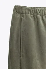 Pantalón verde oliva de tiro alto con bolsillos delanteros y traseros. Cintura elástica ajustable con cordones y pierna ancha.