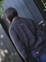 Campera puffer azul marino con diseño acolchado de rombos, cuello de cuero sintético negro, mangas largas abullonadas con puños elásticos y cierre frontal con cremallera.