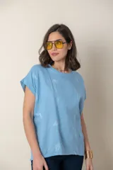 Blusa italiana color celeste con bordado de plumas al tono en el frente, confeccionada en lino y algodón.