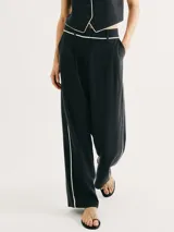 Pantalón negro de corte recto y tiro alto, con bolsillos laterales y detalle de ribete blanco en cintura y laterales.