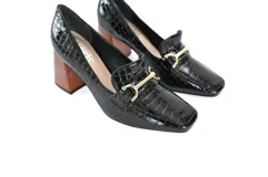 Mocasines negros de charol texturizado con punta cuadrada, detalle de hebilla dorada y tacón geométrico de madera.