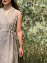 Vestido marrón de lino, corte midi, sin mangas, con cuello mao y cintura elastizada.