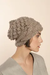 Gorro tejido a mano color crudo, con hilado rueca y variedad de texturas: punto garbanzo y guarda con diseño de trenzas.