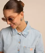 Camisa cropped de jeans celeste con cuello clásico, mangas cortas, cierre frontal con botones y bolsillo en el pecho.