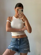 Musculosa blanca con cuello redondo y breteles anchos con ojales metálicos.