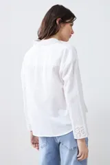 Camisa blanca de manga larga con cuello y puños bordados con calados. Corte clásico y cierre frontal con botones.