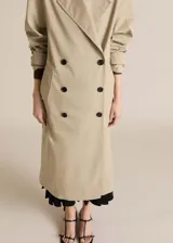 Abrigo largo color beige, de corte oversize, con cuello de solapa, doble botonadura, cinturón desmontable y forro interior.