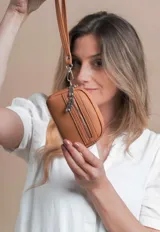 Monedero negro de simil cuero con correa para la mano, diseño práctico y compacto. Bolsillo principal con doble cierre, y un bolsillo frontal pequeño para llevar monedas.