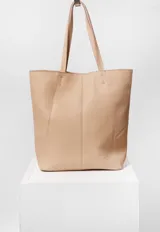 Bolso tote de cuero marrón con costuras a la vista y doble bolsillo interior, uno con cierre. Cierra con broche imán.