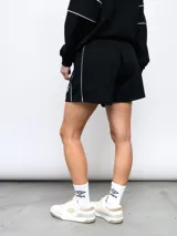 Short deportivo color beige, marca Umbro, de felpa sin frisa con cintura elastizada y cordón ajustable. Presenta ribete color borgoña en los laterales y logo de la marca bordado en el muslo izquierdo.