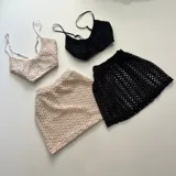 Conjunto de bikini de crochet color blanco, con top de tirantes delgados y falda corta ajustada.