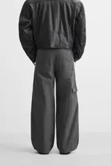 Pantalón gris oscuro de corte amplio, con bolsillos frontales y traseros de parche. Incluye un bolsillo lateral con cierre de cremallera.