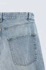 Pantalón de jeans de algodón, corte baggy fit, tiro medio, con efecto lavado en tonos grises y verdes. Presenta cinco bolsillos y cierre frontal con cremallera y botón.