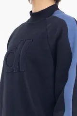 Buzo de algodón grueso con cuello alto y parche con letras dl en el frente. Tiene una franja vertical azul en la manga.
