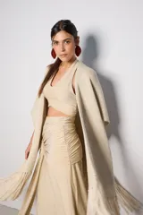 Ruana color beige de tejido de punto con flecos en el ruedo.