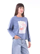 Remera color verde claro con estampado de flores blancas y hojas verdes en el frente.