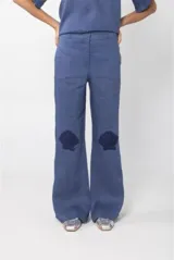 Pantalón de lino azul con tiro medio, pierna recta y apliques de crochet con forma de conchas marinas en las rodillas.