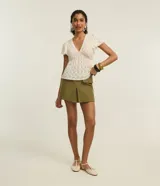 Short pollera de tiro alto color verde oliva, de corte sastrero con solapas delanteras simulando bolsillos y recorte en V en el ruedo.