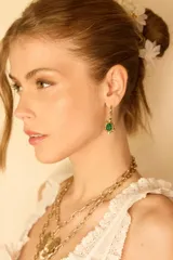 Aros colgantes dorados con forma de tortuga y detalle de piedra verde.