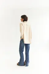 Blazer beige de tela agamuzada, corte recto y solapas clásicas.