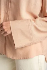 Camisa color salmón de corte oversize, confeccionada en lino y viscosa, con cuello clásico, cierre frontal con botones y mangas largas con puños anchos.
