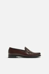 Mocasín de vestir color marrón oscuro, con capellada de cuero, suela a contraste y ligero tacón.