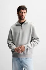 Sudadera color crema de corte recto, con cuello polo y cierre de cremallera metálica.