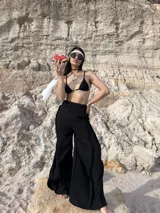 Pantalón negro de tiro alto, corte ancho y fluido, con cintura elástica.