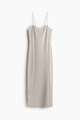 Vestido midi de punto suave color gris, con escote redondo profundo y espalda escotada. Modelo entallado con breteles spaghetti que se entrelazan en bucles y se atan en la espalda.