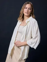 Camisa color crudo con bordado tipo broderie, cuello con solapa, manga tres cuartos y cierre frontal con botones.